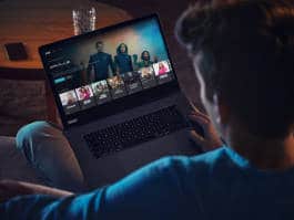 Person browsing movie laptop on lap 
