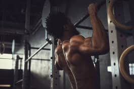 Shirtless man performing pull-ups 