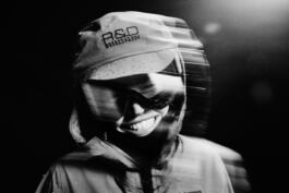 Hedvig Wessel Free ski World Chamption, in wet clothing and goggles, smiling with motion blur effect, against a dark background. Rain droplets visible on the cap. Shot for GoreTex and PeakPerformance 